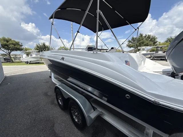 Slide: The Image of The image shows a 2027 Stingray 212 SC boat on a trailer. It features a black and white design with a sunshade. - 5
