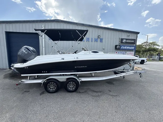 The Image of A 2027 Stingray 212 SC boat on a trailer in front of a building. - 1