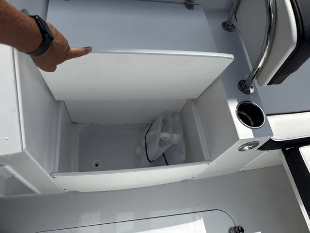 Slide: The Image of An open storage compartment on a 2027 Stingray 212 SC boat with a cup holder beside it. - 10