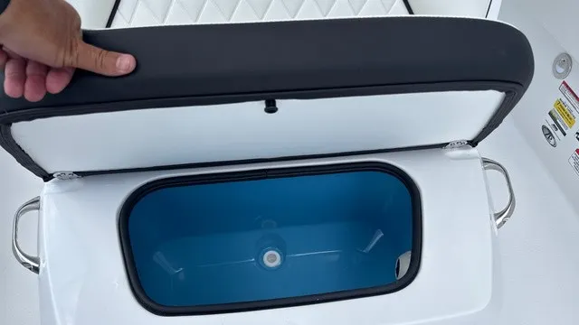 Slide: The Image of An open storage compartment with a blue interior on a boat. A hand holds the lid. - 12