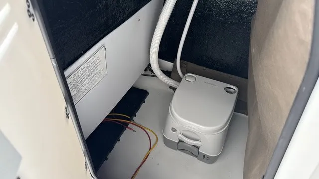 Slide: The Image of The image shows a boat interior with a portable toilet and some wiring. - 16