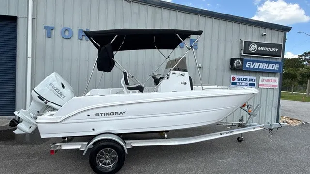 The Image of A white Stingray 173 CC boat from 2027 sits on a trailer in front of a building. - 1