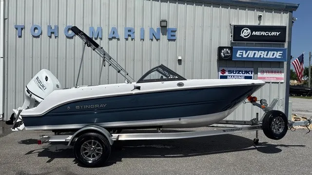 The Image of A 2027 Stingray 172 DC boat on a trailer in front of a building with marine logos. - 1