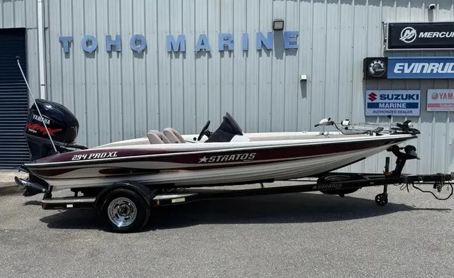 The Image of A 2006 Stratos 294 Pro XL boat on a trailer in front of a building with marine logos. - 1