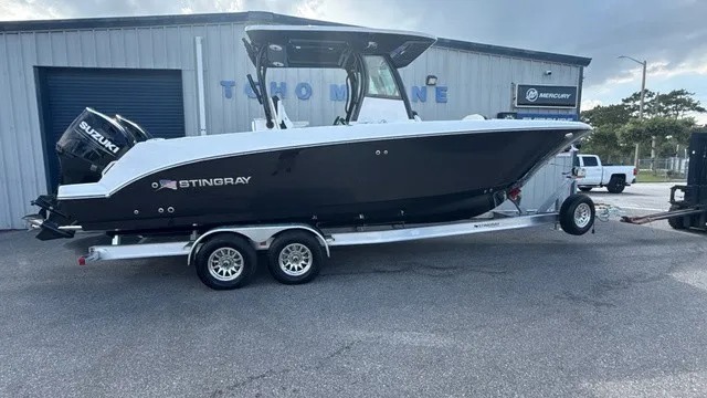 The Image of A black Stingray 253 CC boat from 2027 sits on a trailer in front of a building. - 1