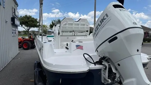 Slide: The Image of A white boat with a Suzuki outboard motor is on a trailer next to a building. - 6