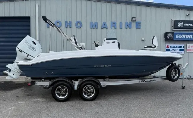 The Image of A 2027 Stingray 206 CC boat on a trailer in front of a building with marine signage. - 1