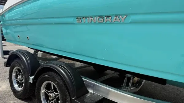 Slide: The Image of A turquoise boat with "Stingray" lettering sits on a trailer with black wheels. - 2