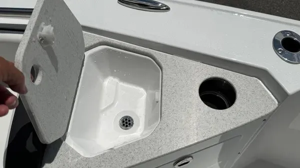 Slide: The Image of An open storage compartment on a boat with a gray surface and round cup holder. - 23