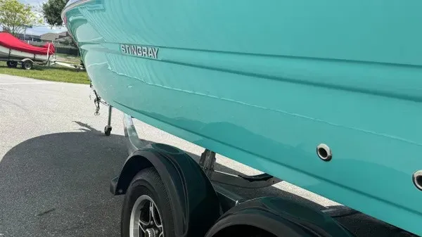 Slide: The Image of A turquoise Stingray 216 CC from 2027 is on a trailer in a parking area. - 7