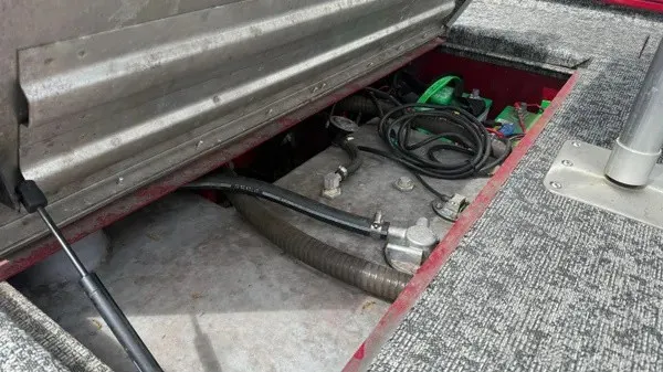 Slide: The Image of An open storage compartment on a boat reveals cables and equipment. The floor is carpeted. - 5
