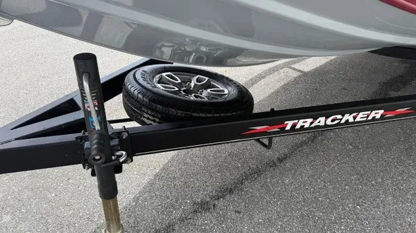 Slide: The Image of A Tracker boat on a trailer with a spare tire, parked on an asphalt surface. - 11