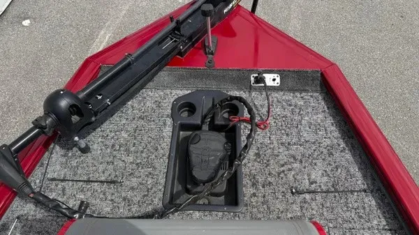 Slide: The Image of The image shows the bow deck of a 2023 Tracker Pro Team 195 TXW Tournament Edition boat. It features a red trim and gray carpeting with a mounted motor. - 13