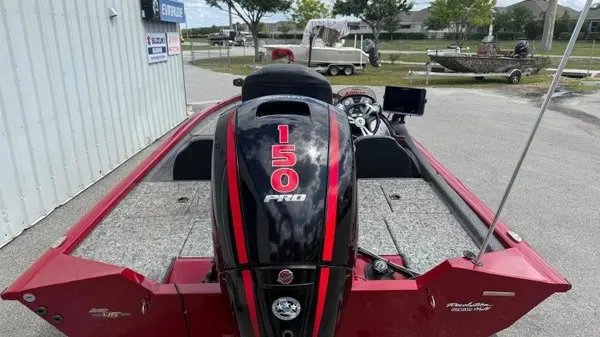 Slide: The Image of A red Tracker boat with a 150 HP Pro engine, parked on a concrete lot. - 6