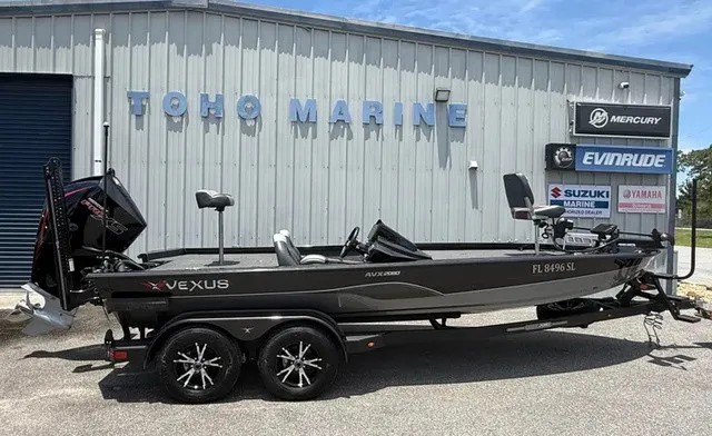 The Image of A 2019 Vexus AVX 2080 boat on a trailer in front of a building with marine logos. - 1