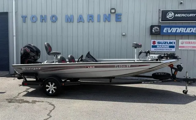 The Image of A silver 2018 Ranger RT188 boat on a trailer in front of a building with marine signs. - 1