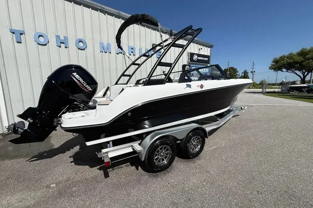 Slide: The Image of A 2027 Stingray 20 SBX boat on a trailer in front of a building. - 3
