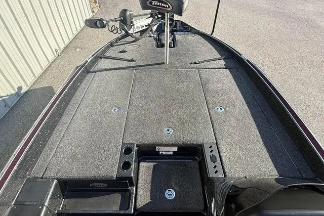 Slide: The Image of The image shows the deck of a 2019 Triton 20 TrX Patriot boat with gray carpeting. - 13