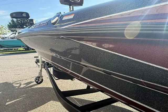 Slide: The Image of A 2019 Triton 20 TrX Patriot boat with a shiny, dark red hull on a trailer. - 3