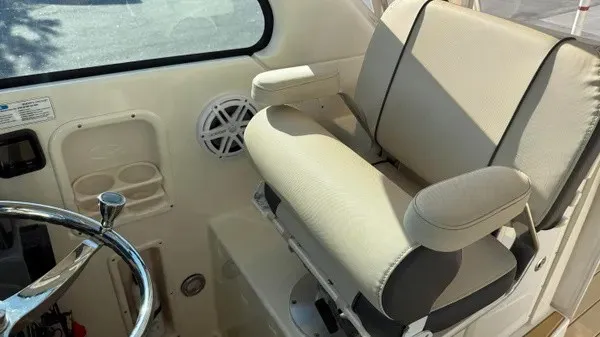 Slide: The Image of A beige captain's chair with armrests in a boat, next to a steering wheel and cup holders. - 17
