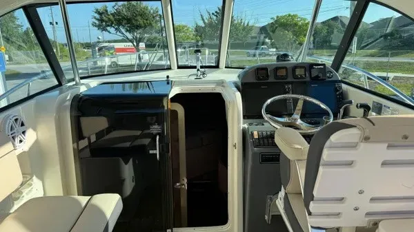 Slide: The Image of The image shows the cockpit of a 2007 Pursuit OS 335 Offshore. It features a helm with steering wheel and instruments, and a cabin door. - 11