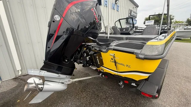 Slide: The Image of A yellow 2022 Nitro ZV19 boat with a large outboard motor, parked beside a building. - 3