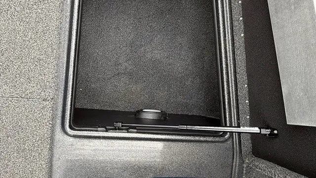 Slide: The Image of An open storage compartment with carpeted flooring and a hydraulic strut. - 13
