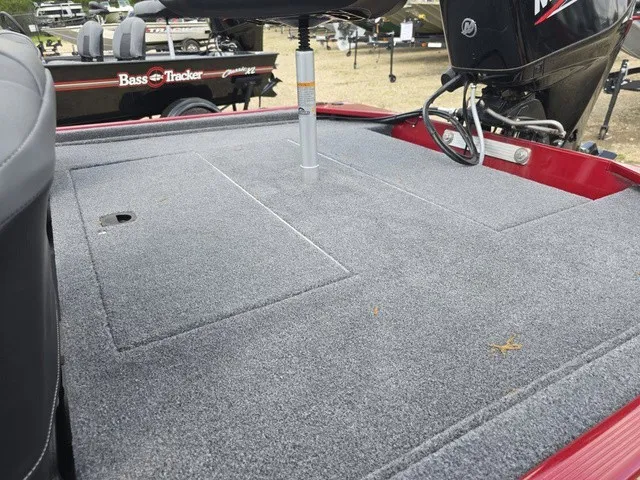 Slide: The Image of The image shows the gray carpeted deck of a 2025 Tracker Bass Tracker Classic XL. - 16
