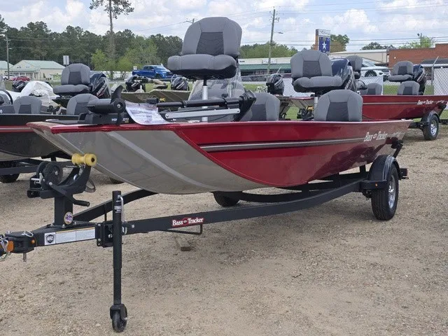 The Image of A red 2025 Bass Tracker Classic XL boat sits on a trailer in a gravel lot. - 1