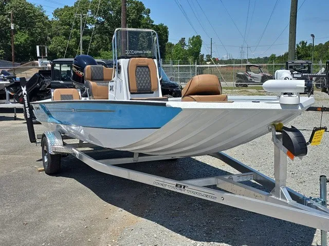 Slide: The Image of A 2026 Xpress SW20B boat on a trailer, featuring blue and white paint with brown seats. - 5