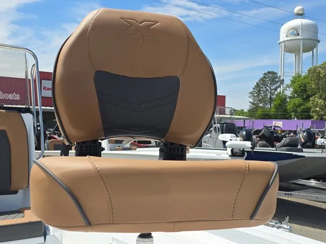 Slide: The Image of A brown boat seat with a black insert, surrounded by other boats and a water tower in the background. - 19