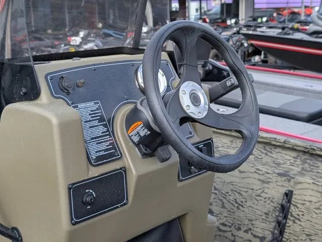 Slide: The Image of The image shows the helm of a Tracker Grizzly 1860 CC boat with a steering wheel and instruments. - 25