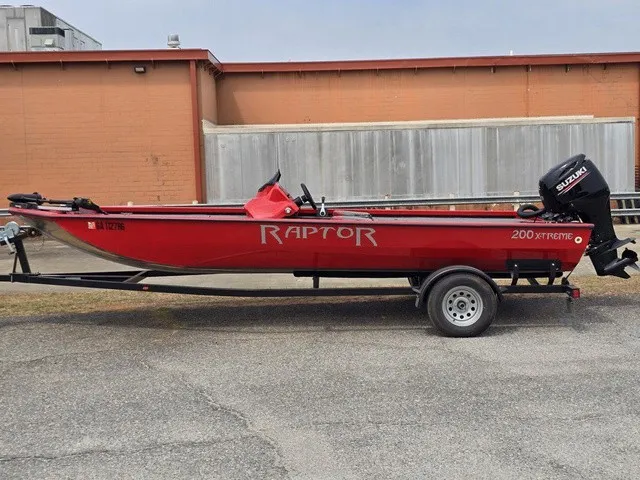 Slide: The Image of A red Caravelle Raptor 200 boat on a trailer, featuring a Suzuki outboard motor. - 10