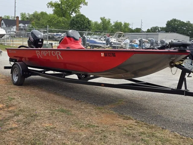 Slide: The Image of A red 2021 Caravelle Raptor 200 boat on a trailer, parked on a gravel lot. - 5