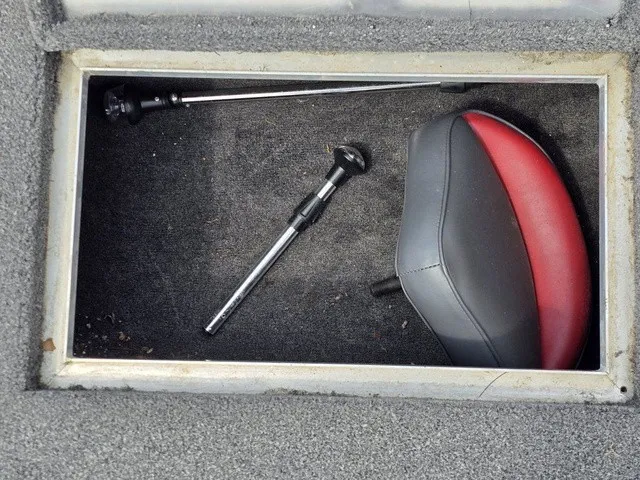 Slide: The Image of An open storage compartment with a red and black seat cushion and two metal rods. - 24