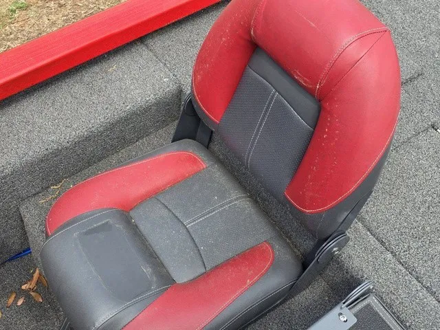 Slide: The Image of A red and black boat seat with padded design on gray carpeted flooring. - 26