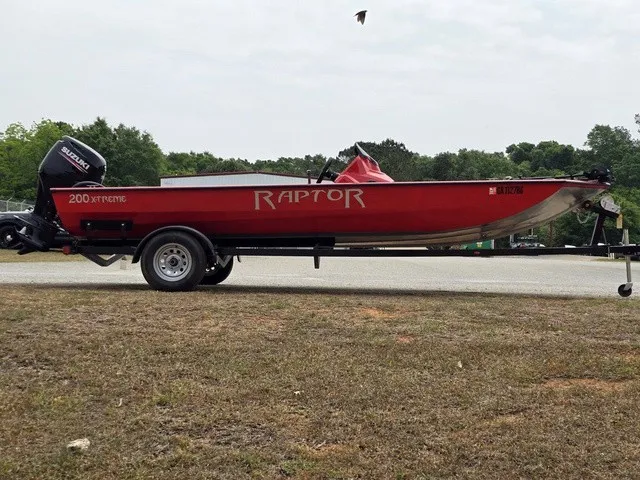 Slide: The Image of A red 2021 Caravelle Raptor 200 boat on a trailer, featuring a Suzuki outboard motor. - 6