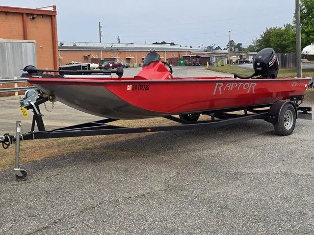 Slide: The Image of A red 2021 Caravelle Raptor 200 boat on a trailer in an industrial area. - 2