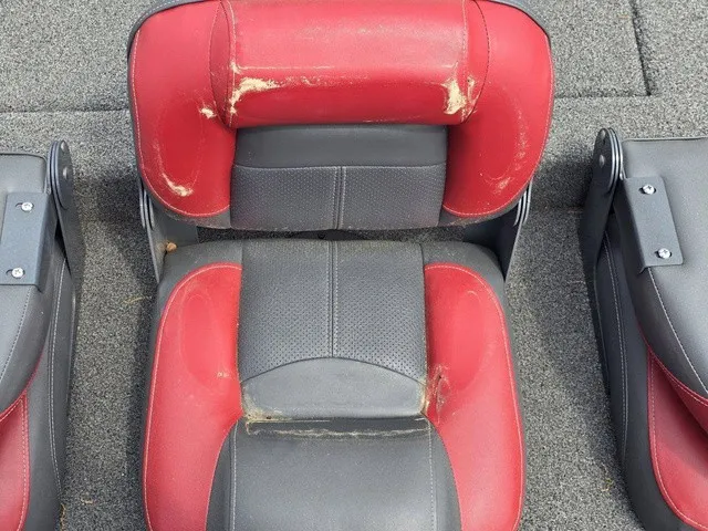 Slide: The Image of Red and black boat seats with signs of wear on gray carpeted flooring. - 20