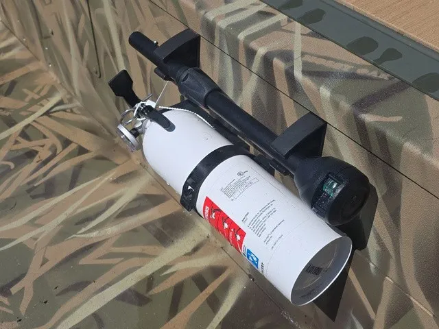 Slide: The Image of A fire extinguisher is mounted on the side of a camouflaged boat. - 21