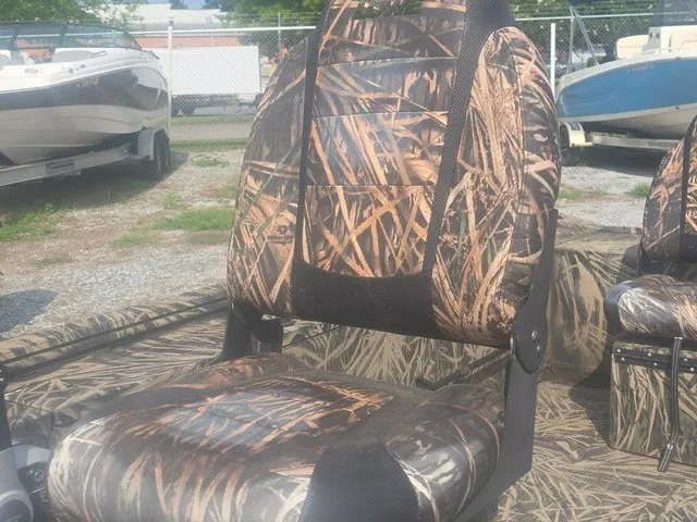 Slide: The Image of A camo-patterned boat seat surrounded by other boats on a gravel lot. - 15