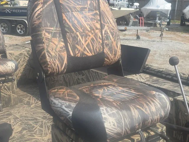 Slide: The Image of A camo-patterned boat seat surrounded by other boats on a gravel lot. - 24