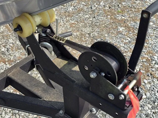 Slide: The Image of Close-up of a boat trailer winch with yellow rollers on a gravel surface. - 22