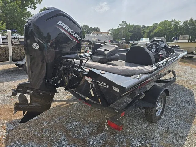 Slide: The Image of A black 2020 Tracker Pro Team 175 TXW boat on a trailer in a gravel lot. - 9