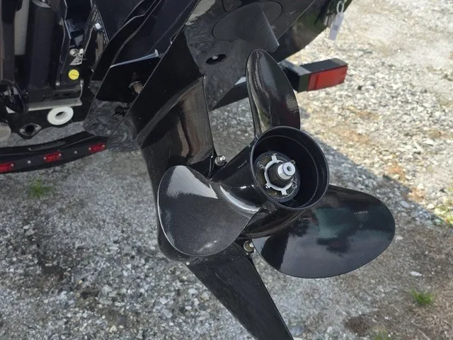 Slide: The Image of Close-up of a shiny black propeller on a boat, set on a gravel surface. - 9
