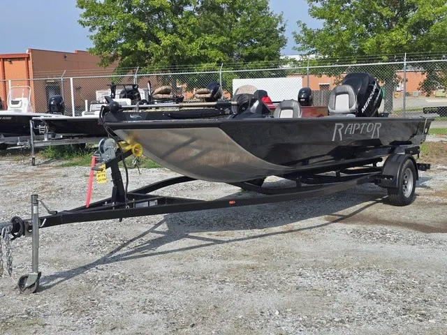 Slide: The Image of A black 2020 Caravelle RAPTOR boat on a trailer in a gravel lot. - 2