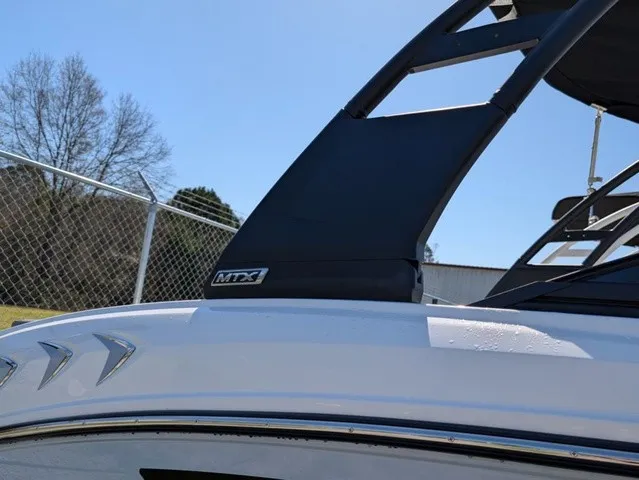 Slide: The Image of A modern boat with a black MTX wake tower, parked outdoors. - 8