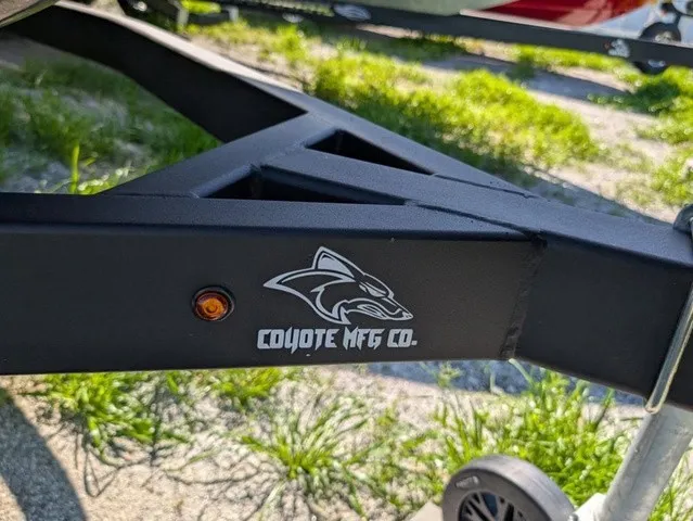 Slide: The Image of A black boat trailer with the Coyote Mfg Co. logo is on a grassy surface. - 5