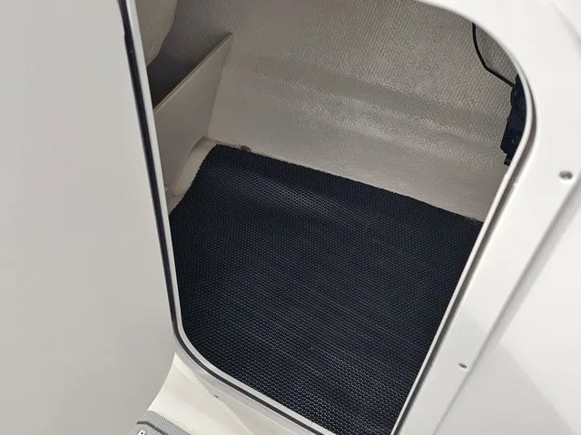 Slide: The Image of A view into a boat's interior with dark carpet flooring and white walls. - 34