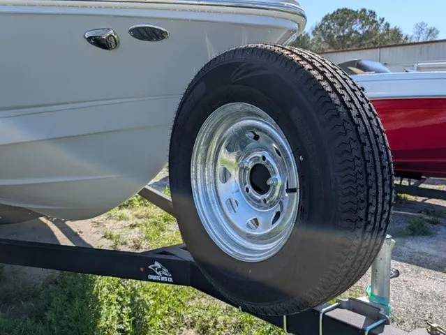 Slide: The Image of A Chaparral 23 SSi boat on a trailer with a spare tire. It is outdoors. - 4